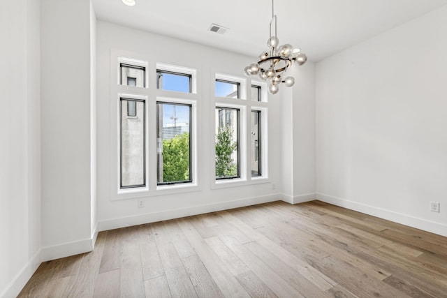 unfurnished room featuring an inviting chandelier and light hardwood / wood-style floors