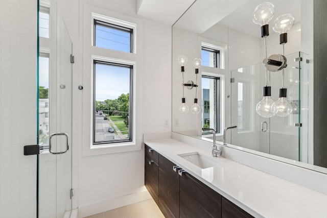 bathroom featuring a shower with door, vanity, and a healthy amount of sunlight