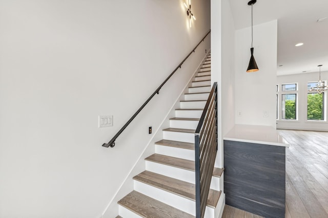 stairs with a chandelier and hardwood / wood-style floors