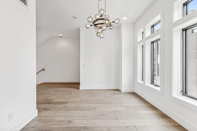 unfurnished room with a chandelier and light wood-type flooring