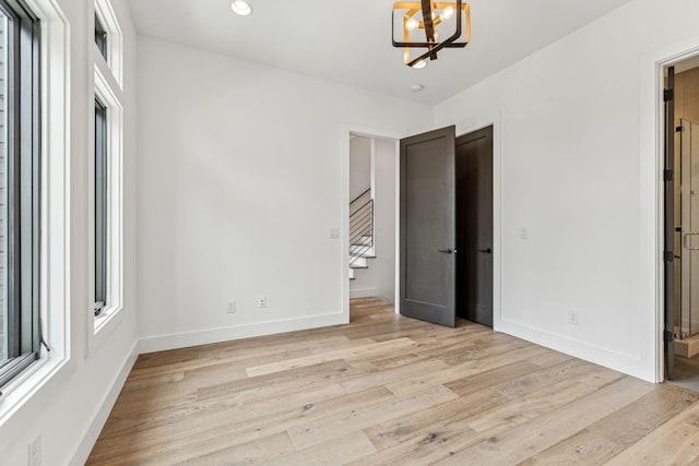 unfurnished bedroom featuring a notable chandelier and light wood-type flooring