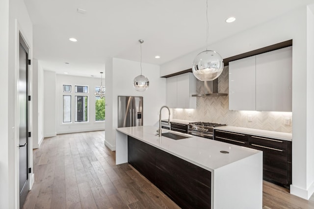 kitchen featuring sink, high quality appliances, an island with sink, pendant lighting, and white cabinets