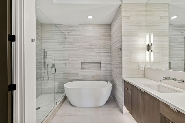 bathroom with shower with separate bathtub, tile walls, and vanity