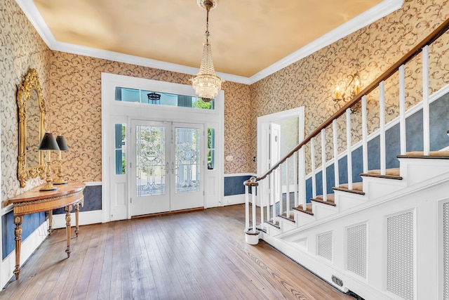 entrance foyer featuring ornamental molding, french doors, a chandelier, and hardwood / wood-style floors