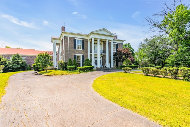 neoclassical home featuring a balcony and a front yard