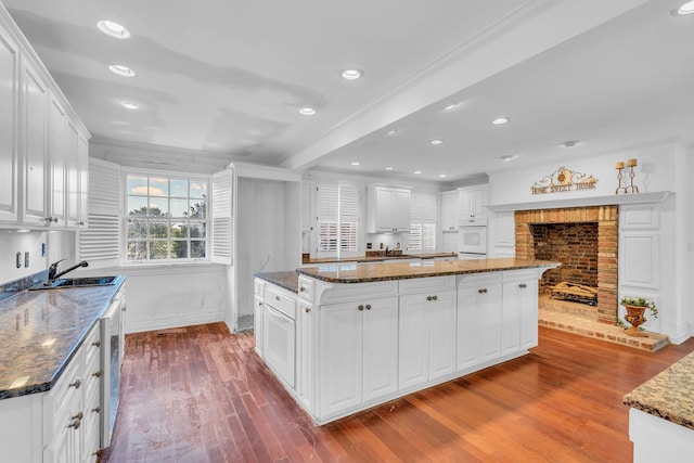 kitchen with white cabinets, dark stone counters, and light hardwood / wood-style flooring