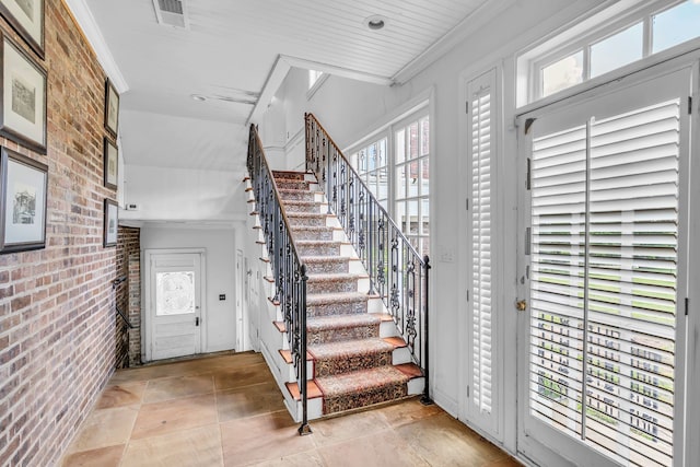 staircase featuring brick wall and light tile patterned floors