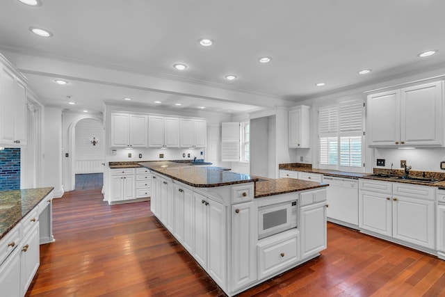 kitchen with white appliances, white cabinets, dark stone counters, dark hardwood / wood-style flooring, and a kitchen island