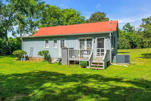 back of property with a yard and central AC