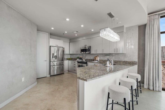 kitchen featuring pendant lighting, a kitchen bar, decorative backsplash, kitchen peninsula, and stainless steel appliances