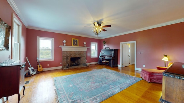 living room with hardwood / wood-style flooring, crown molding, ceiling fan, and a fireplace