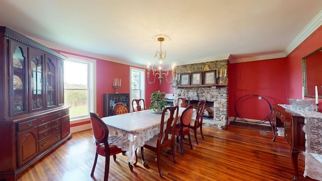 dining space with ornamental molding, a fireplace, a chandelier, and wood-type flooring