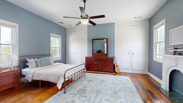 bedroom featuring ceiling fan, multiple closets, and light wood-type flooring