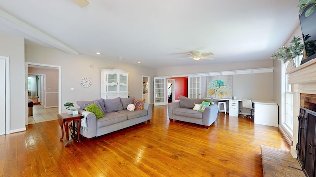 living room with ceiling fan, a brick fireplace, light wood-type flooring, and french doors