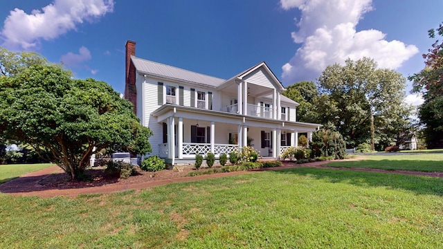 view of front facade with a porch, a balcony, and a front lawn