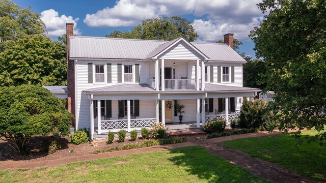 view of front facade with a balcony, covered porch, and a front lawn