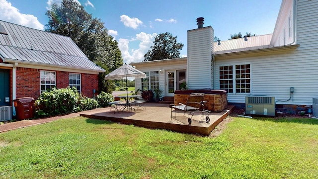 rear view of property with a patio, a yard, and central AC