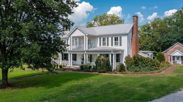 view of front facade featuring a balcony, covered porch, and a front lawn