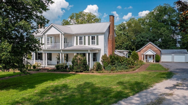 view of front of home with a garage, a balcony, an outbuilding, covered porch, and a front lawn