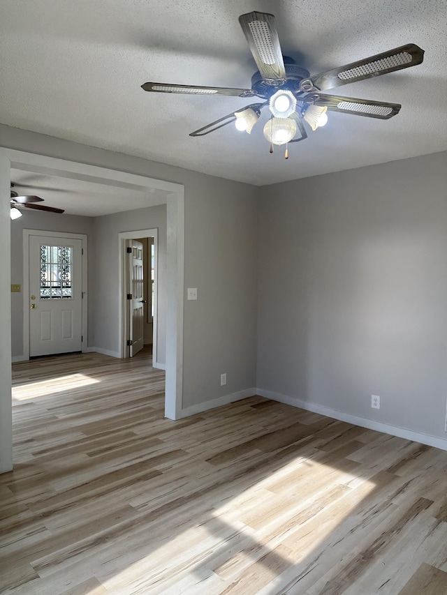 empty room with ceiling fan, light hardwood / wood-style floors, and a textured ceiling