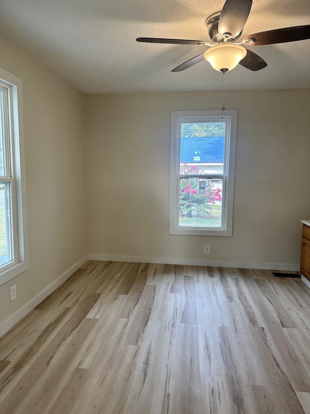 spare room with ceiling fan, light hardwood / wood-style floors, and a textured ceiling