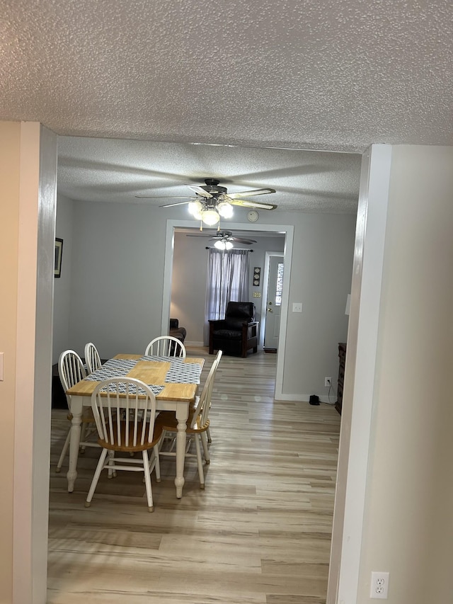 dining space with a textured ceiling, ceiling fan, and light wood-type flooring