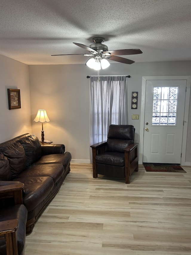 living room with ceiling fan, light hardwood / wood-style flooring, and a textured ceiling