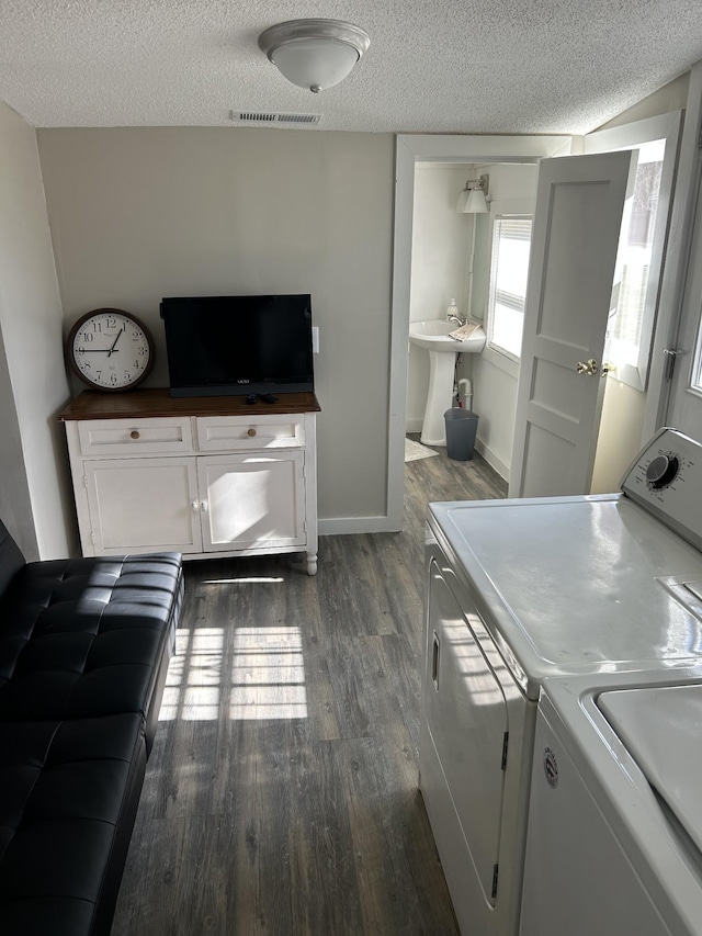 laundry room with dark wood-type flooring, washer and clothes dryer, sink, and a textured ceiling