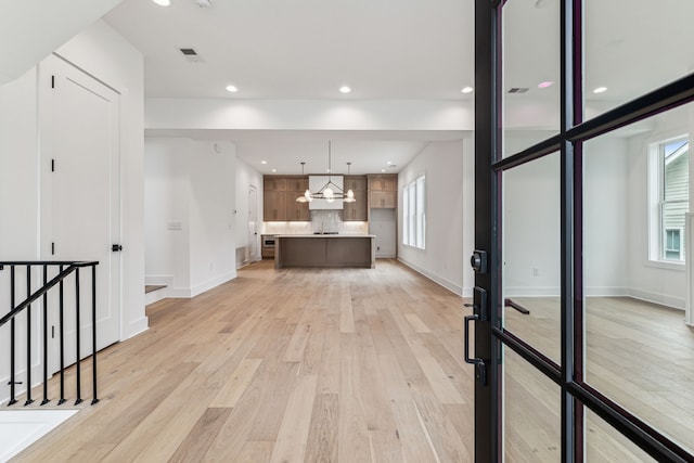 unfurnished living room with sink and light wood-type flooring