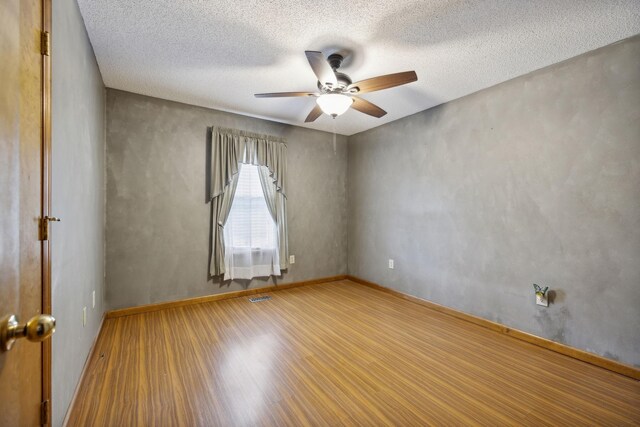 empty room with a textured ceiling, ceiling fan, and light hardwood / wood-style floors