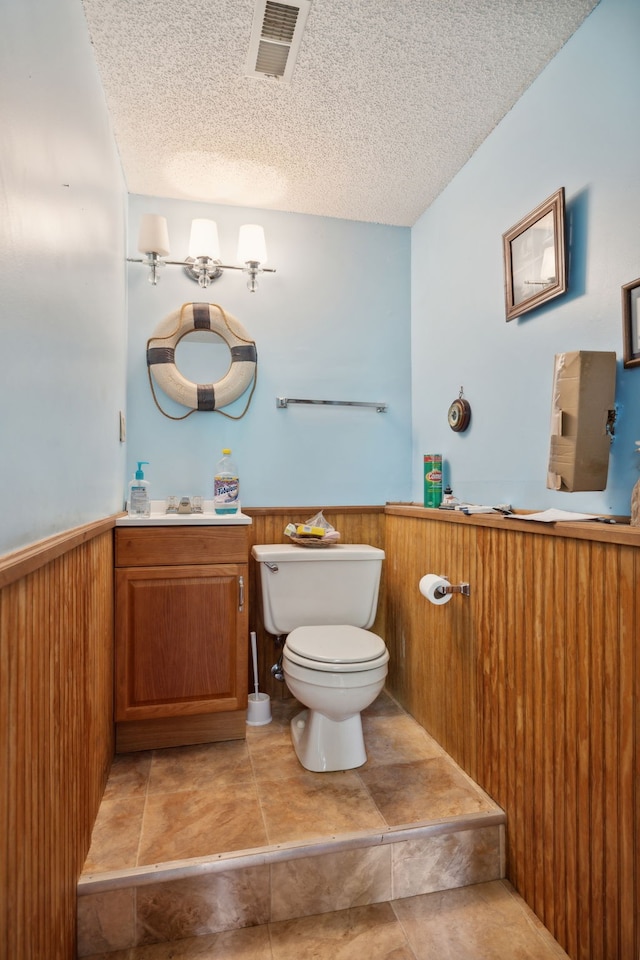 bathroom featuring tile patterned flooring, toilet, vanity, and a textured ceiling