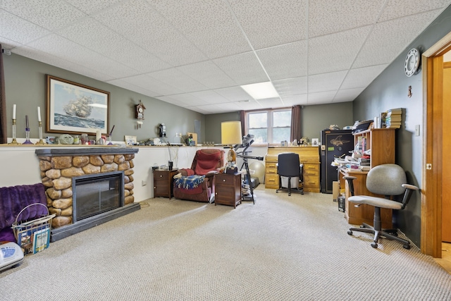 carpeted living room featuring a stone fireplace and a paneled ceiling