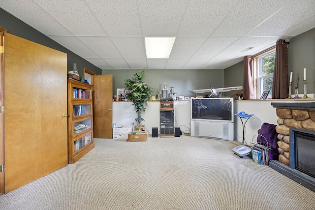 living room featuring a fireplace, a paneled ceiling, and carpet flooring