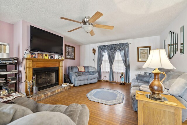 living room with a textured ceiling, a fireplace, hardwood / wood-style flooring, and ceiling fan