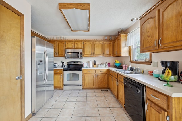 kitchen featuring sink, a textured ceiling, stainless steel appliances, and light tile patterned floors