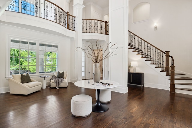 entryway with dark wood-type flooring, ornate columns, and a towering ceiling