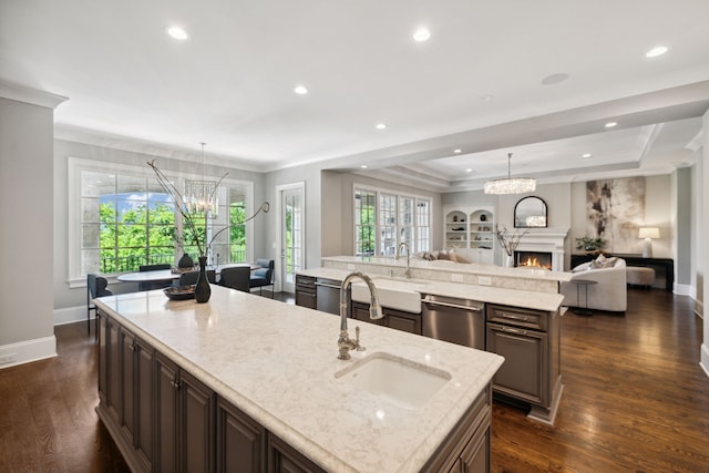 kitchen featuring hanging light fixtures, a large island with sink, stainless steel dishwasher, dark hardwood / wood-style floors, and dark brown cabinetry