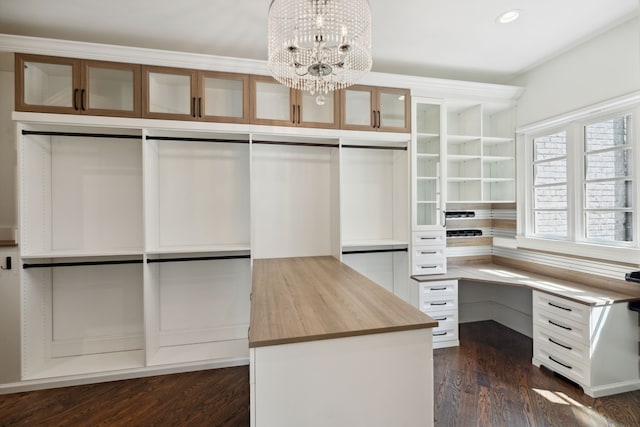 spacious closet with a notable chandelier and dark wood-type flooring