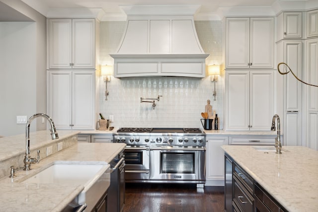 kitchen with dark hardwood / wood-style floors, range with two ovens, sink, light stone countertops, and custom exhaust hood