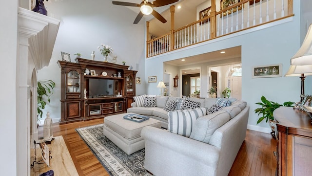 living room featuring hardwood / wood-style flooring, ceiling fan, and a high ceiling