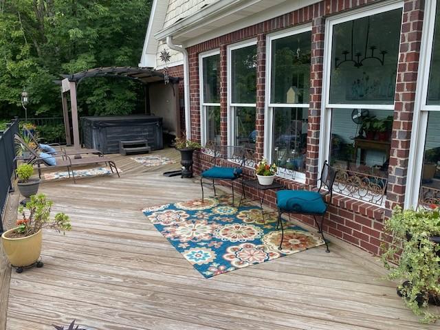 wooden terrace with a pergola and a hot tub