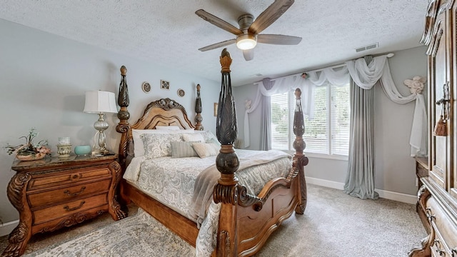 bedroom featuring ceiling fan, light carpet, and a textured ceiling