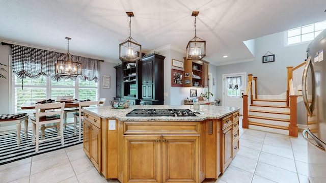 kitchen featuring light stone counters, stainless steel appliances, decorative light fixtures, and a center island