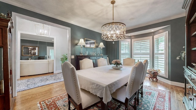 dining room featuring ornamental molding, light hardwood / wood-style floors, and a notable chandelier