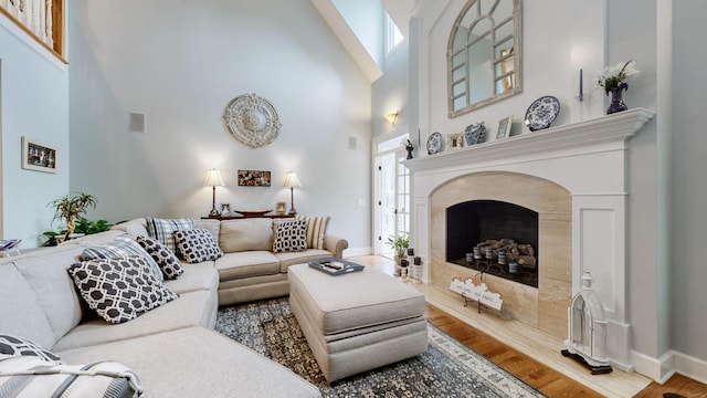 living room featuring a fireplace, wood-type flooring, and a high ceiling