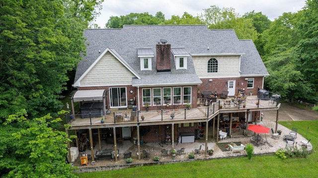 rear view of property featuring a wooden deck and a patio area