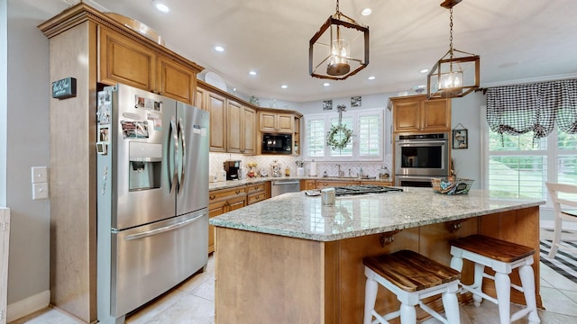 kitchen with appliances with stainless steel finishes, decorative light fixtures, decorative backsplash, a center island, and light stone countertops