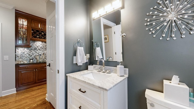 bathroom with hardwood / wood-style floors, tasteful backsplash, vanity, toilet, and an inviting chandelier