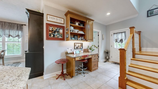 bar with light stone counters, built in desk, ornamental molding, and light tile patterned flooring