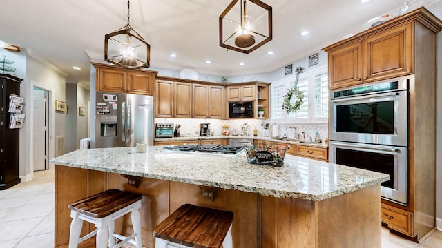 kitchen featuring stainless steel appliances, hanging light fixtures, a center island, and light stone counters